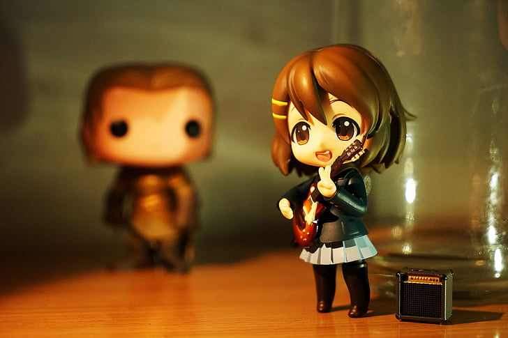 female brunette anime character playing guitar figurine on brown wooden surface