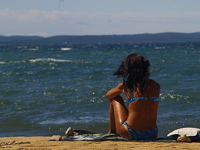 woman sitting on seashore during daytime