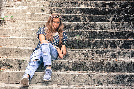 woman in black and white shirt sitting on concrete stair
