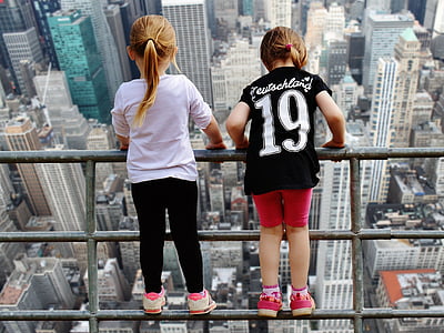 two girls standing on gray metal railing