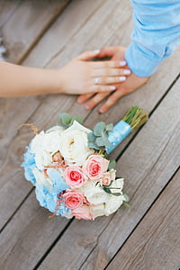 white, pink, and blue roses bouquet near couple holding hands