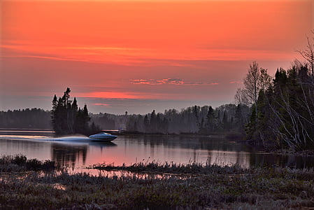 white speedboat on body of water at sunset