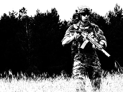 man walking on grass while holding rifle