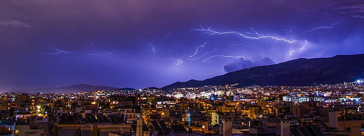 lightning occurring above mountain near city