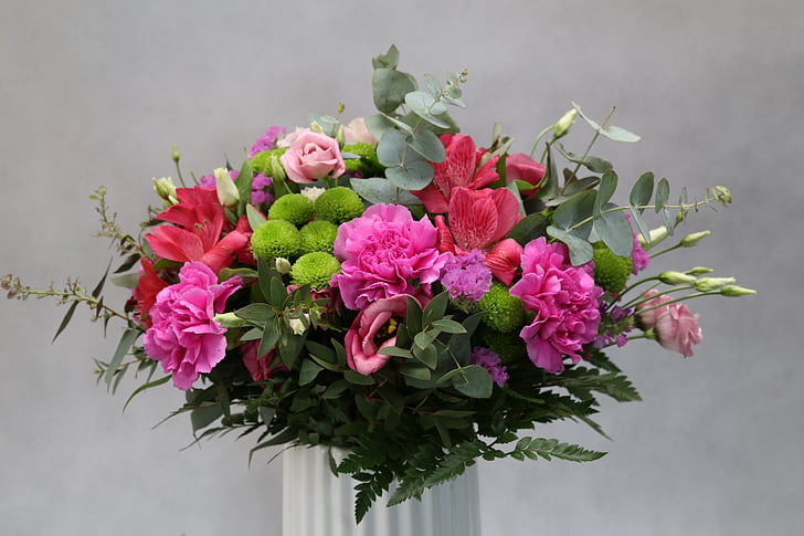 pink, red, and green petaled flowers in white vase close up photo