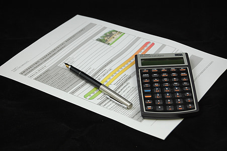 black and gray desk calculator with pen