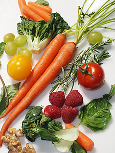 carrots, strawberries, tomatoes, and cabbage arrange on white textile