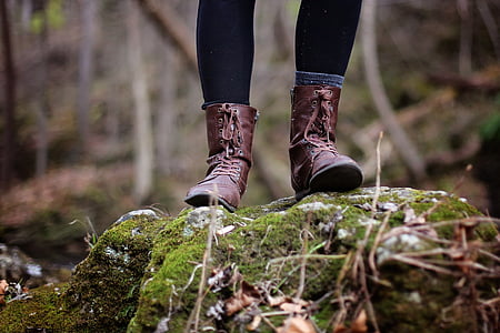 person wearing brown leather hiking boots stepping on the stone