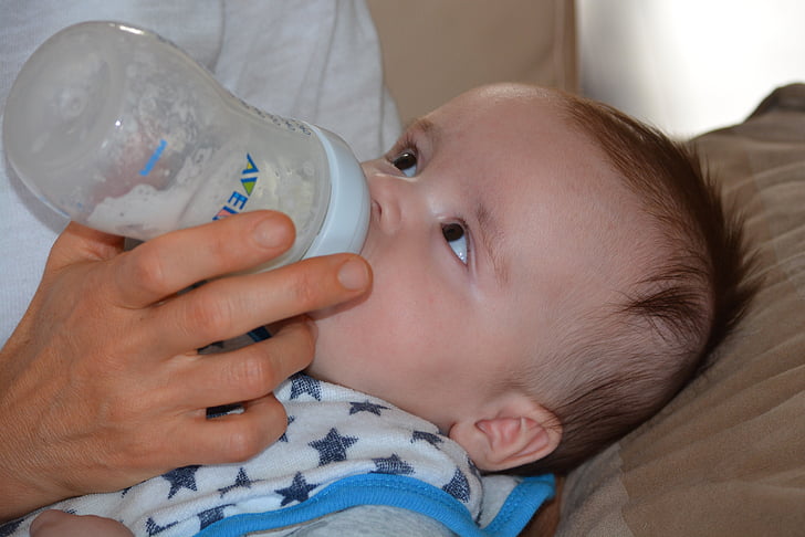 person feeding baby milk in bottle