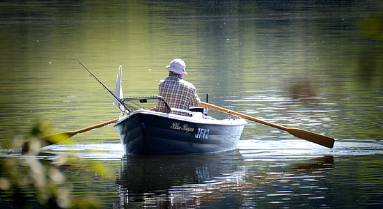 man riding black boat using oar