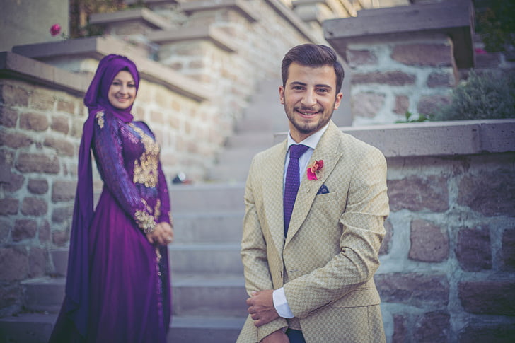 man wearing gray suit and woman wearing purple abaya wedding dress