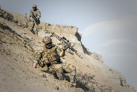 soldier in realistic camouflage suit holding assault rifle sliding downhill