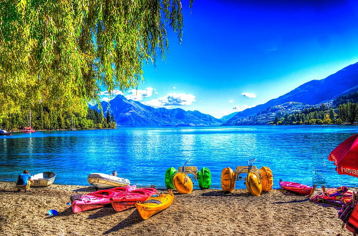 assorted-color kayak and boat near body of water background of mountains