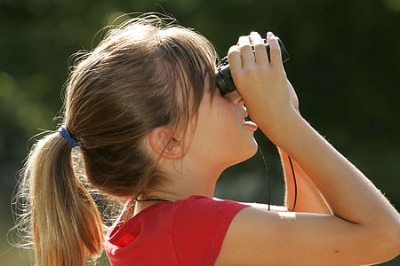 woman holding binoculars while looking up