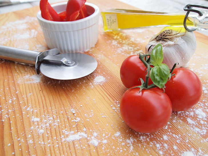 tomatoes beside garlic and pizza slicer