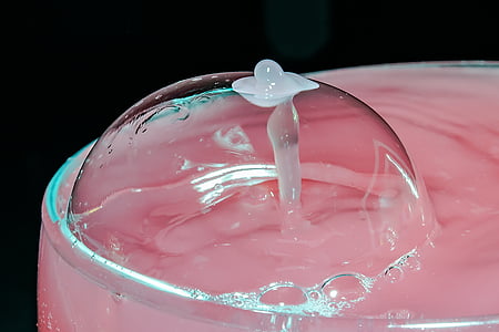 bubble on clear drinking glass filed with pink-colored beverage