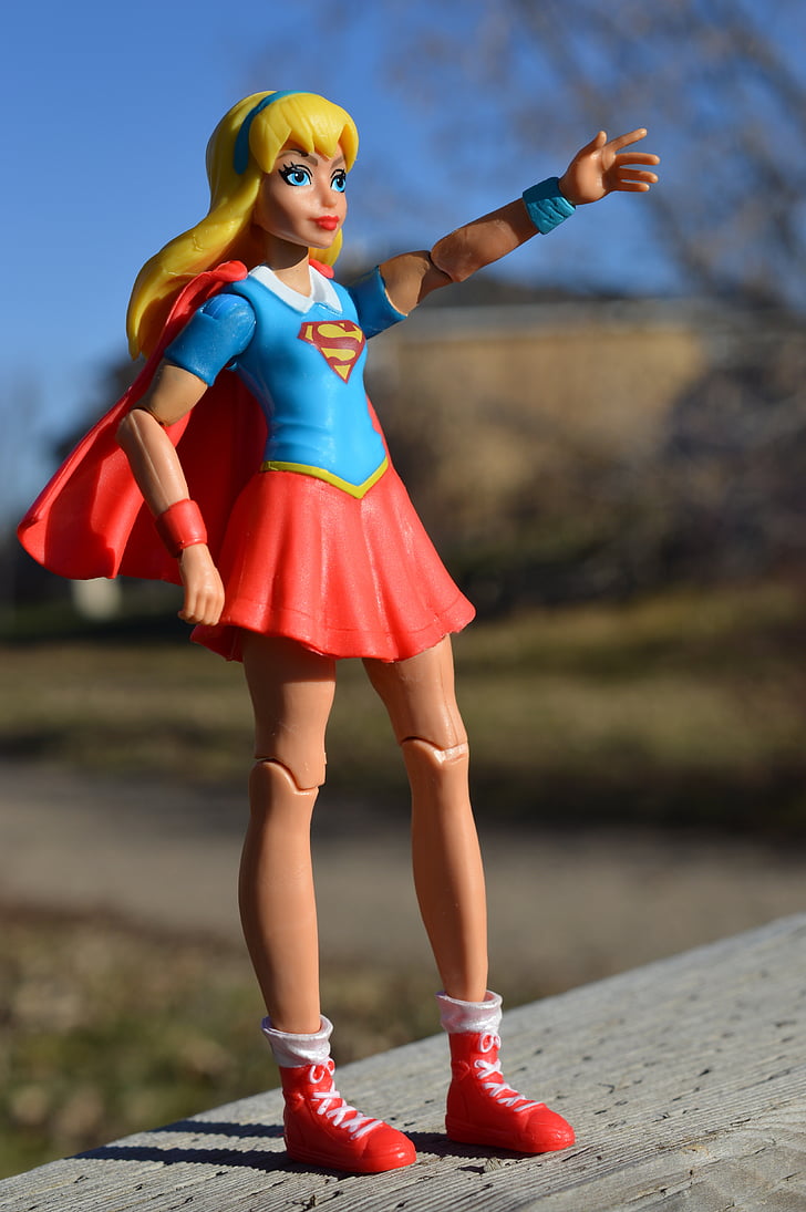 macro photograph of DC Super Hero Girls Supergirl action figure on gray wooden surface