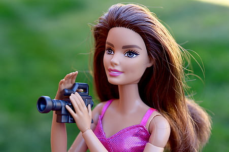 selective focus photography of blonde-haired female doll holding video camera