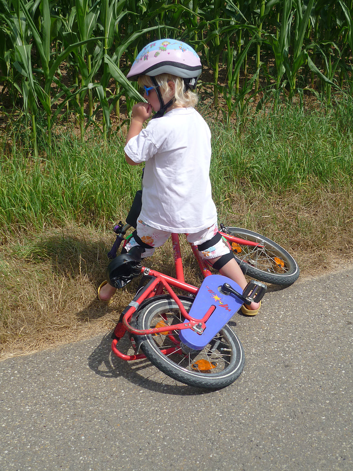 boy riding red bicycle on road