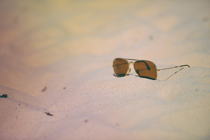 photo of brown tinted sunglasses on gray sand