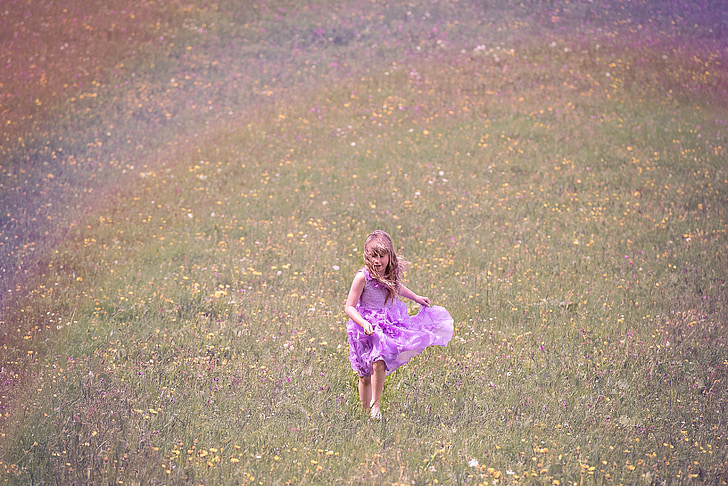 girl wearing purple dress running on grass field