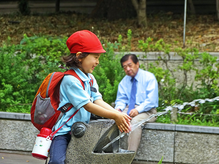 girl in school uniform washing her hands near sitting man