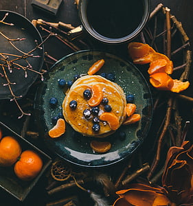 top view of pancakes topped with blueberries and peeled oranges on plate