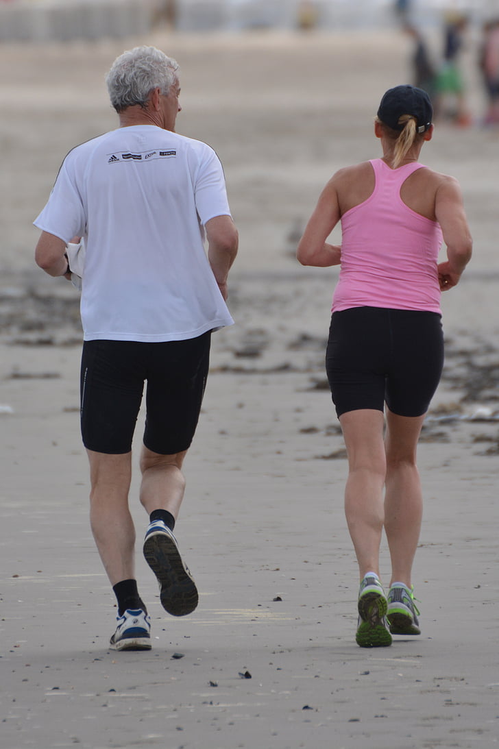 man in white top jogging beside woman in pink racerback top