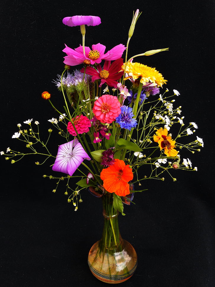 red-blue-and-yellow petaled flowers in amber glass vase