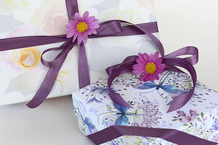 two white floral gift boxes with purple ribbons