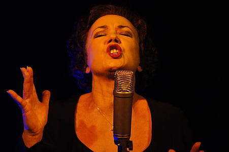woman wearing black scoop-neck top singing in front of condenser microphone