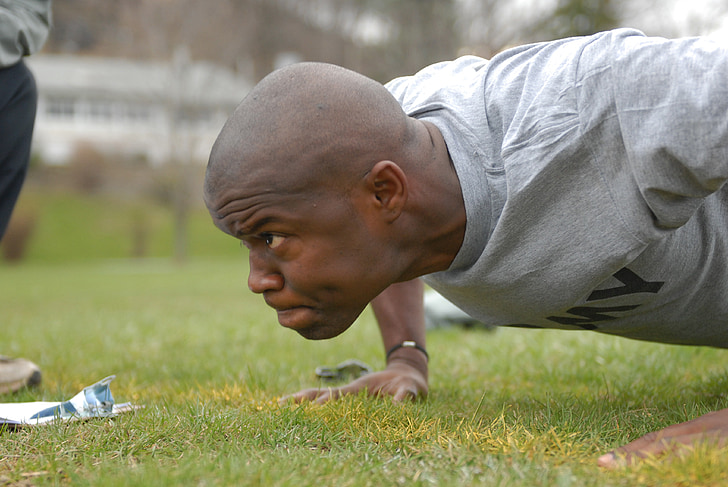 Royalty-Free photo: Man wearing gray army shirt doing push up on the field