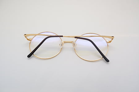 gold framed eyeglasses on white surface