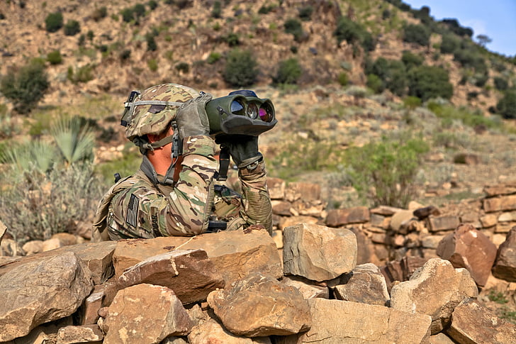 soldier behind rock using binocular
