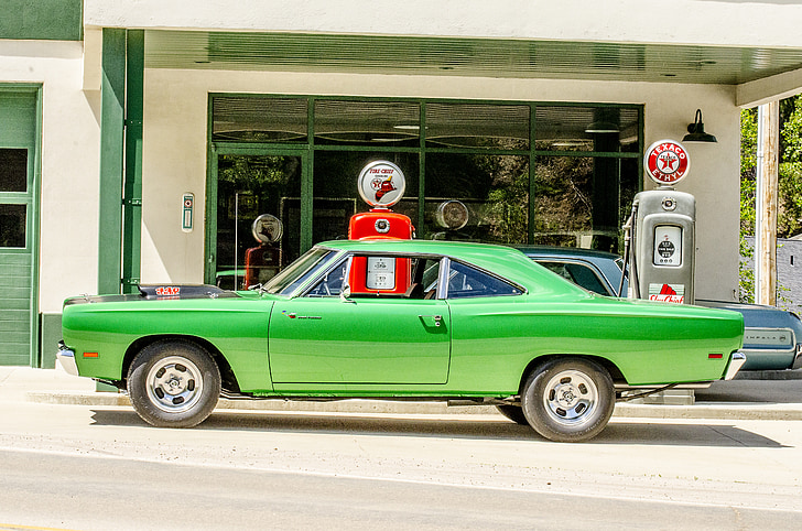 green muscle car parked on gasoline station