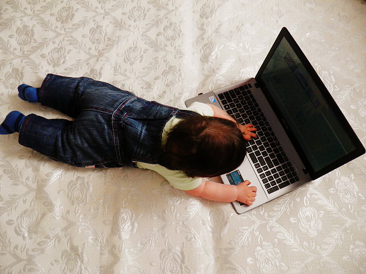 high-angle photography of baby playing laptop