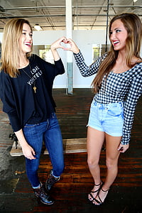 two smiling women making heart handsigns