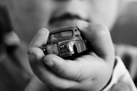 graycale photography of toddler holding car toy