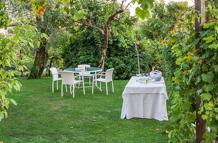white and green patio set near table with white tablecloth near trees and green grass field at daytime