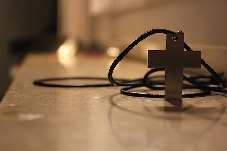 selective focus photography of silver-colored cross pendant