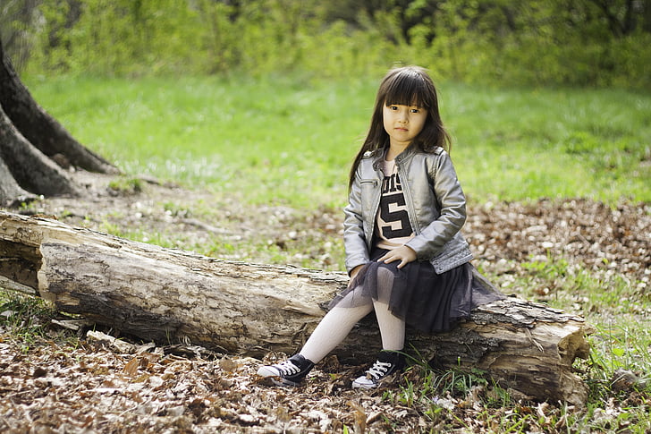 girl sitting on tree tuck on grass field