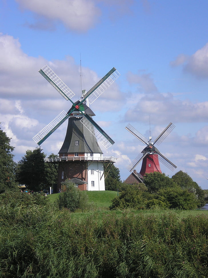 two red and gray wooden windmills surrounded with trees