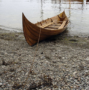brown wooden boat on seashore at daytime