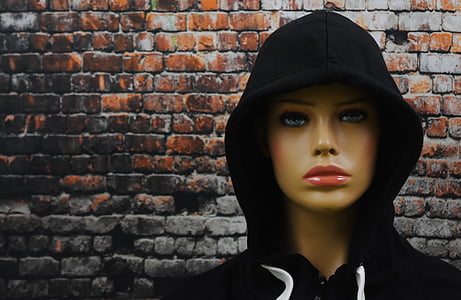 mannequin wearing hoodie in front brick wall