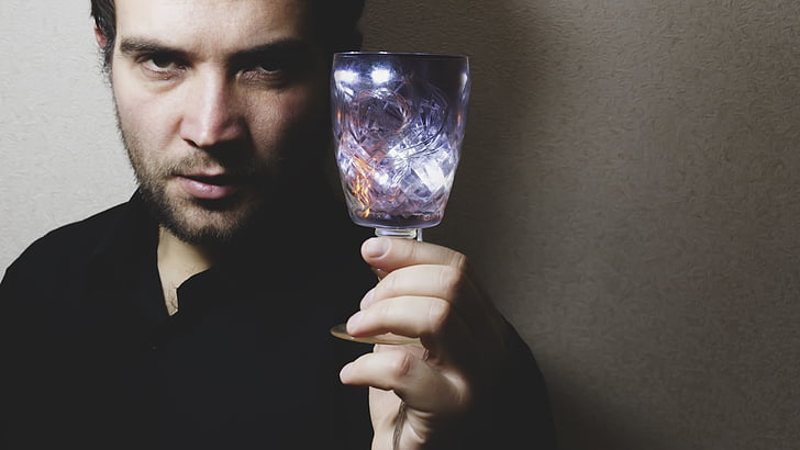 man in black top holding purple translucent drinking glass