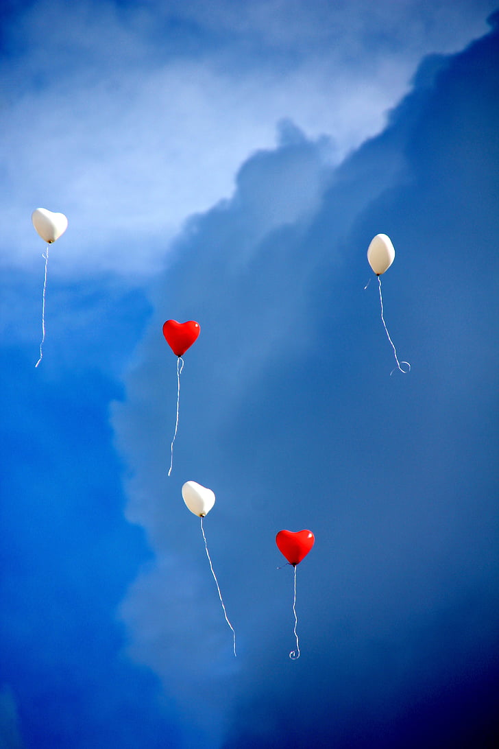 two red and three white heart balloons in the sky