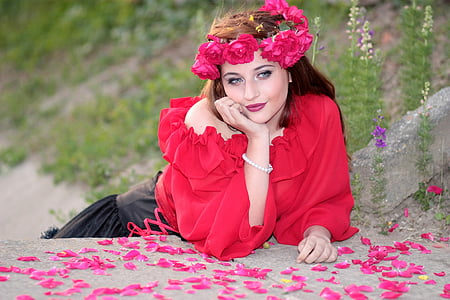 woman wearing red one-shoulder shirt with red rose artificial headdress