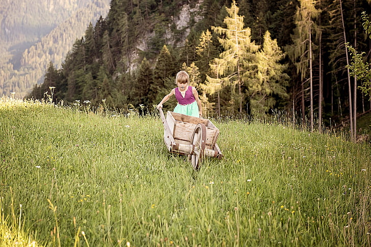girl pushing a wheelbarrow in forest
