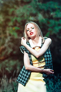 woman in yellow collared dress wearing black and white checkered vest taking a pose during daytime