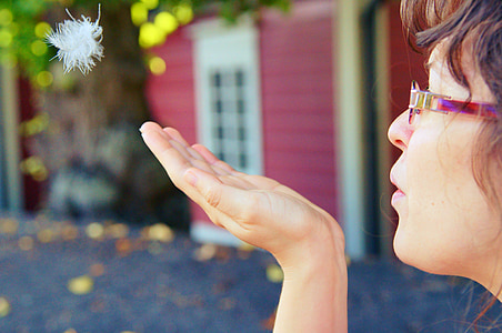 shallow focus photography of woman blowing dandelion on her palm